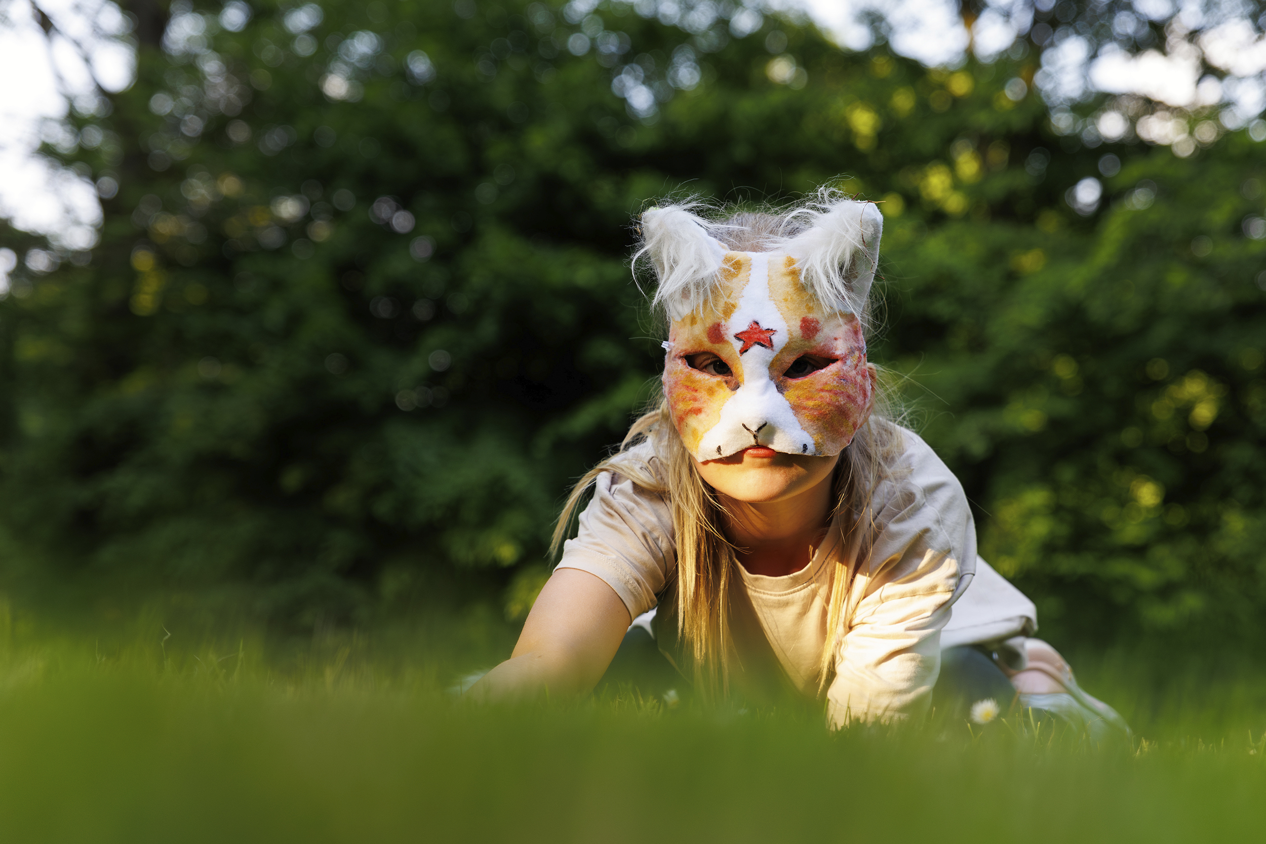 Cute young little kid girl wear cat furry mask enjoy have fun playing outdoors in forest street park. Children therian wild animal character trendy fan culture
