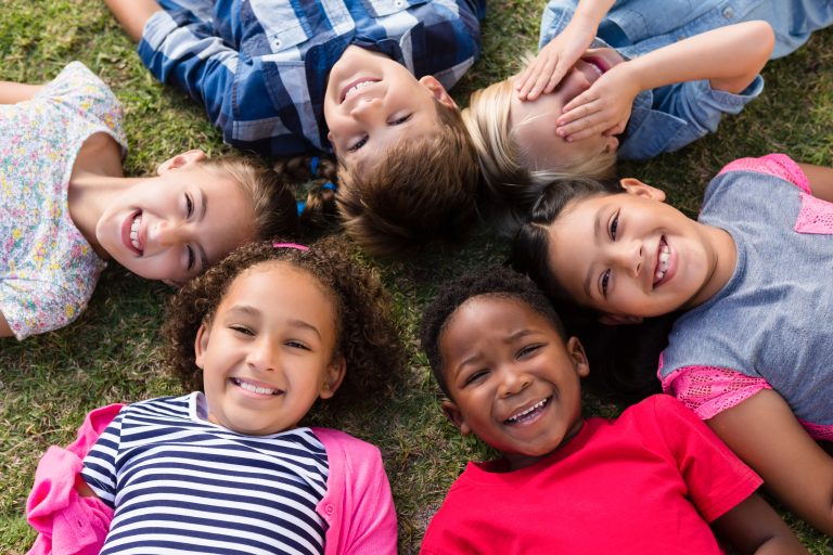 Directly above portrait of children lying on field in yard