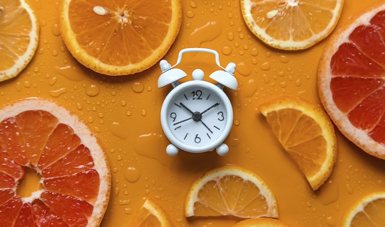 Clock and citruses summer time concept. Selective focus